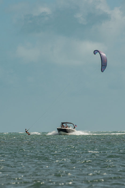 Downwinders — kiteboarder riding with a boat on the water in Miami